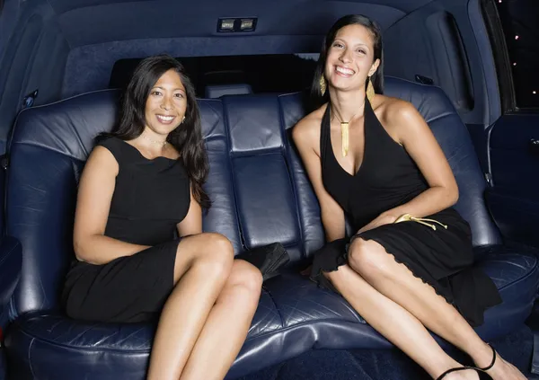 Two woman in formal outfits in backseat of car