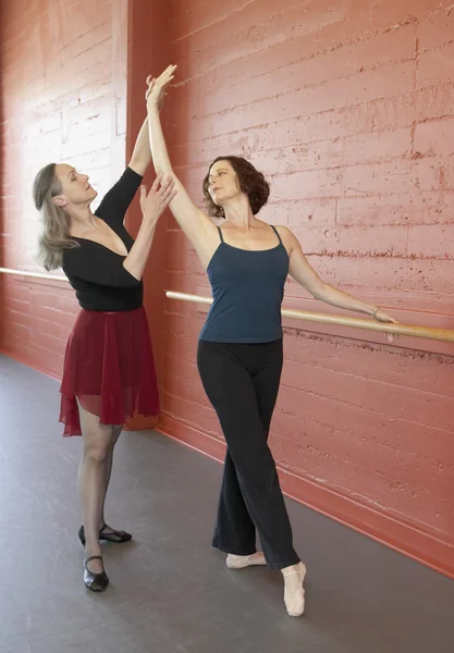 Mature female ballet teacher helping adult female student