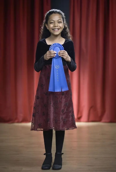 Mixed Race girl holding blue ribbon on stage