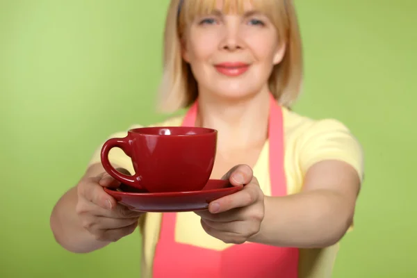 Зрелая домохозяйка, дающая чашку чая или кофе — стоковое фото