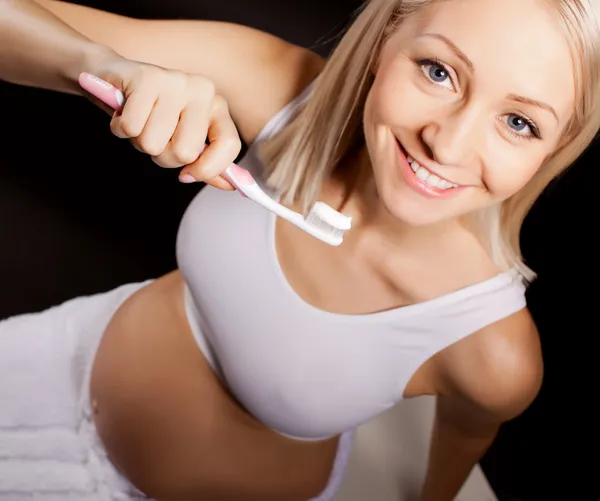 Positive pregnant blond woman checks her teeth — Stock Photo, Image