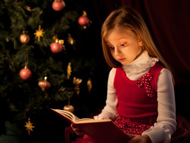 küçük kız Noel ağacının yakınında sihirli kitap okuma
