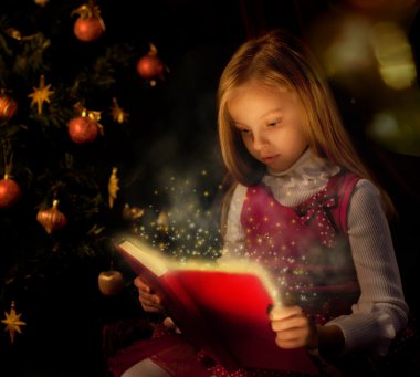küçük kız Noel ağacının yakınında sihirli kitap okuma