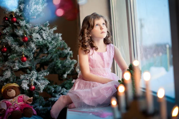 Littlle girl dreaming near Christmas tree — Stock Photo, Image