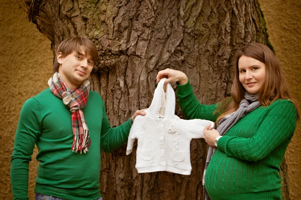 Coppia incinta che guarda i vestiti per bambini nel parco — Foto Stock