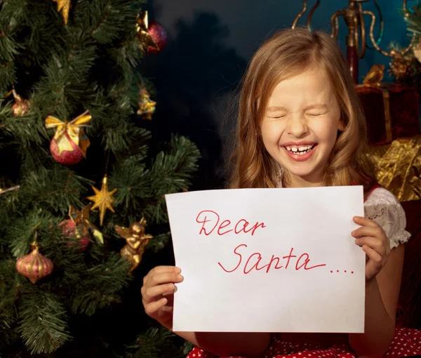 Klein meisje in de buurt van de kerstboom en brief voor santa — Stockfoto