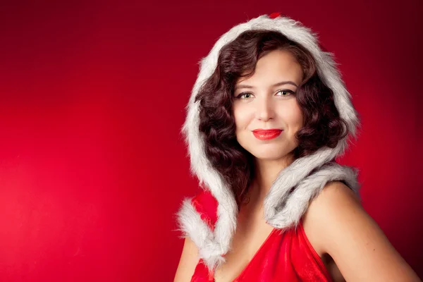 Weihnachtsmann-Mädchen blickt auf rotem Hintergrund in die Kamera — Stockfoto