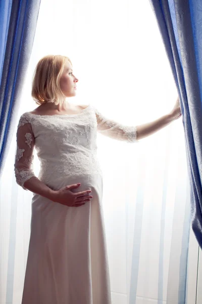 Hermosa novia embarazada posando contra ventana —  Fotos de Stock