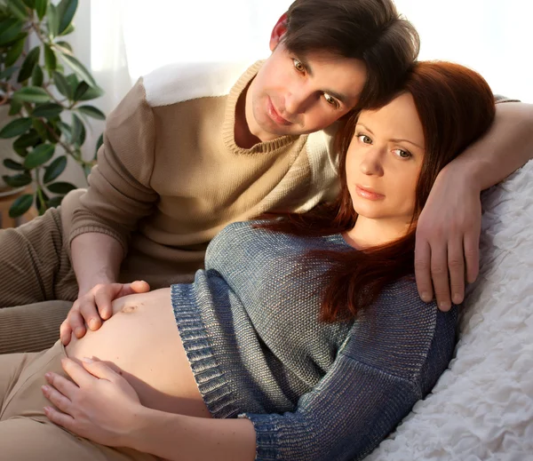 Pregnant couple relaxing on sofa, dreaming. Tenderness — Stock Photo, Image