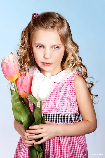 Fröhliches blondes kleines Mädchen mit Tulpen — Stockfoto