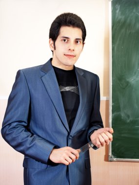 Kendine güvenen genç öğretmen ve klasik kara tahta arka plan