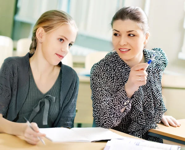 Portrait of a teacher explaining something to a smiling schoolbo — Stock Photo, Image