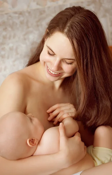 Glücklich aussehendes Baby mit Strickmütze und Mutter beim Toben — Stockfoto