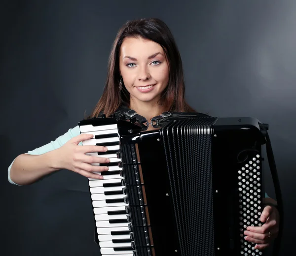 Musikermädchen spielt Ziehharmonika vor dunklem Hintergrund — Stockfoto