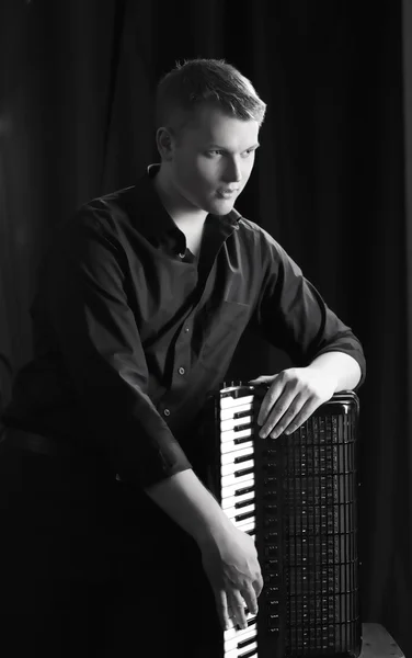 Musicien joue de l'accordéon sur un fond sombre — Photo