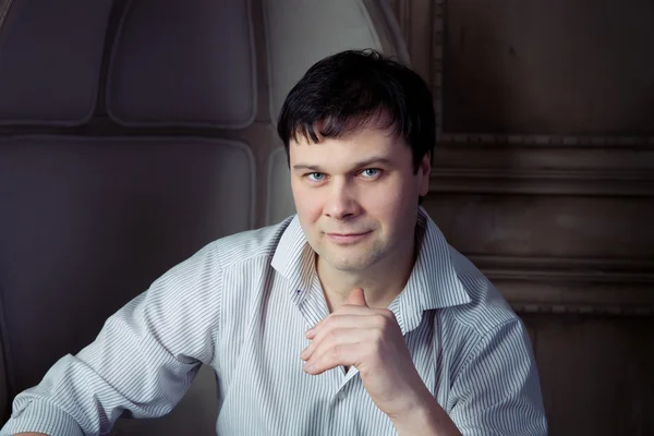 Handsome man sitting in an old chair — Stock Photo, Image