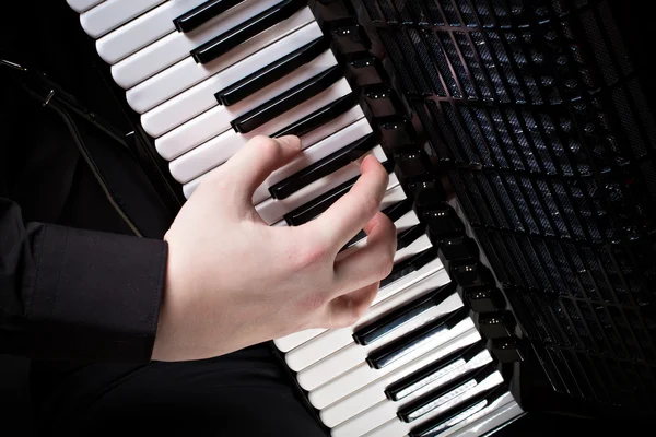 Музыкант играет на аккордеоне на темном фоне — стоковое фото