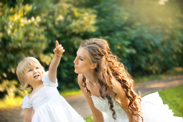 Bride and smartly dressed girl playing in the park. Mother and daughter. Problem of child when mother is in second marriage — Stock Photo, Image