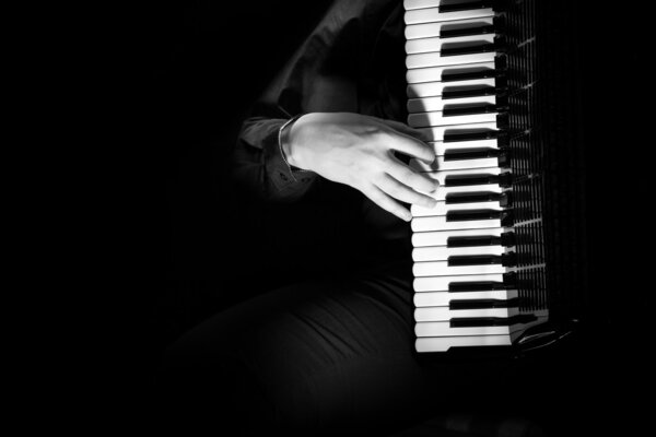 musician plays the accordion against a dark background