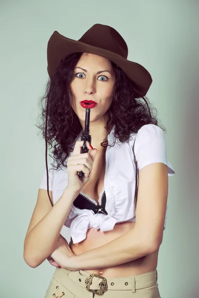 Brunette lange haren meisje veel plezier bij het poseren met pistool in studio in c — Stockfoto