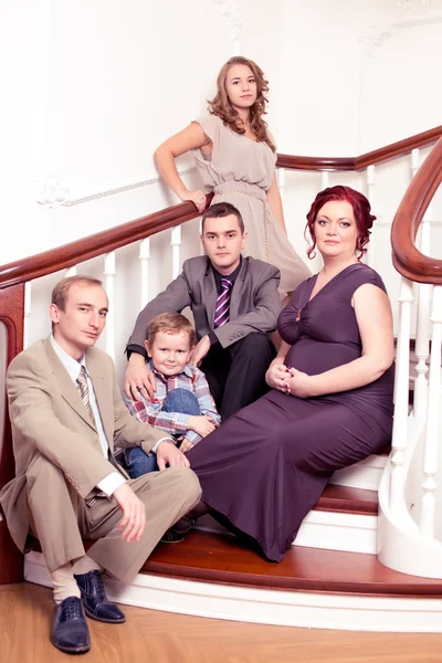 Family sitting on staircase smiling — Stock Photo, Image