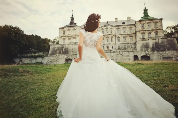 Великолепная невеста, идущая рядом с замком — стоковое фото
