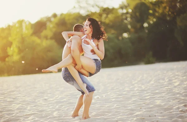 Heterosexuella par på stranden har kul, i en bakgrundsbelyst — Stockfoto