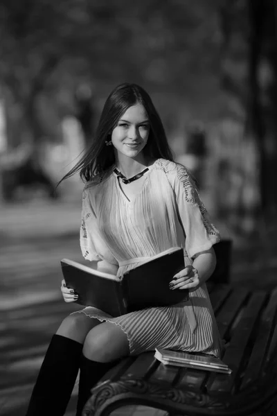 young beautiful woman reading book outside