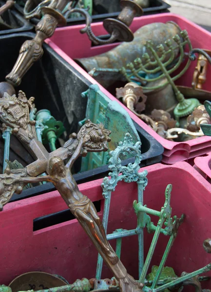 Crucifix, menorah and iron scrap in pink boxes at flea market — Stock Photo, Image