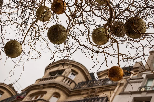 Closeup of branches with gold and silver Christmas balls. Building and grey sky on background. Paris at evening. — Stock Photo, Image