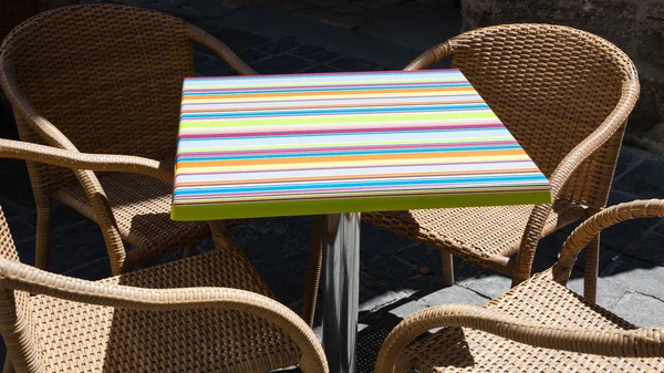 Colorful striped table and four wicker armchairs. Outdoors. — Stock Photo, Image