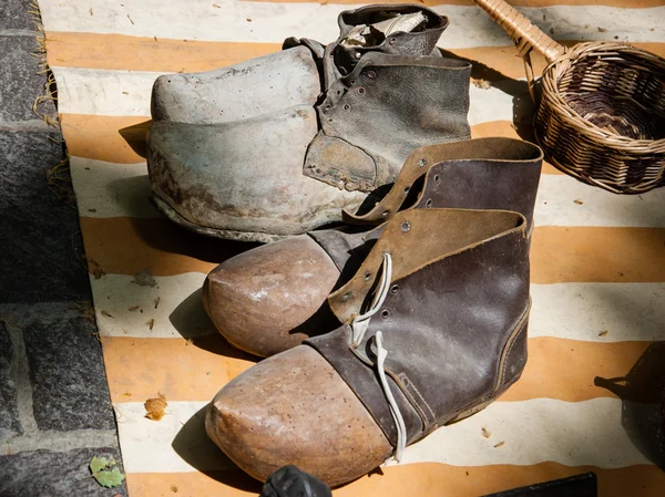 Two pairs of old dirty wooden shoes with leather and shoelaces at flea market. — Stock Photo, Image