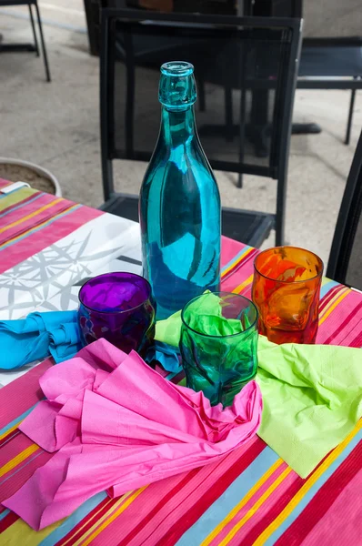 Tres vasos de colores, botella y servilletas — Foto de Stock