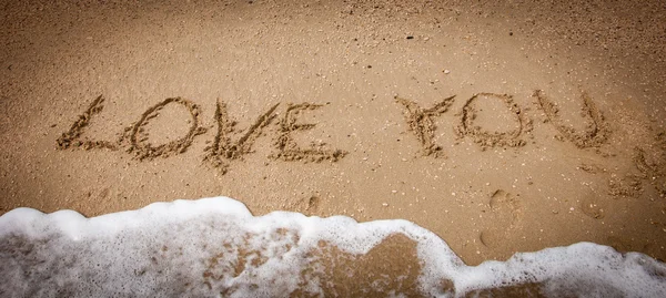 LOVE YOU inscrição na areia da praia e onda do mar — Fotografia de Stock