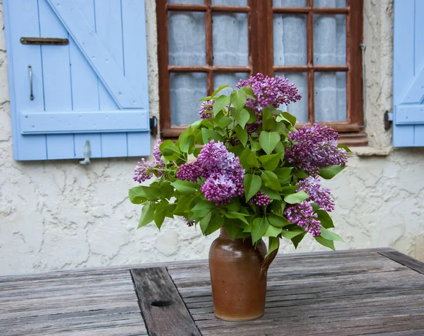 Ramo de color lila en jarra de cerámica sobre mesa de madera envejecida —  Fotos de Stock