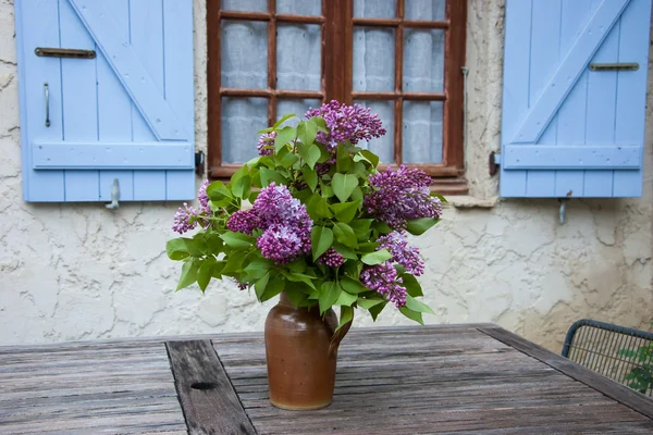 Ramo de color lila en jarra de cerámica sobre mesa de madera envejecida —  Fotos de Stock