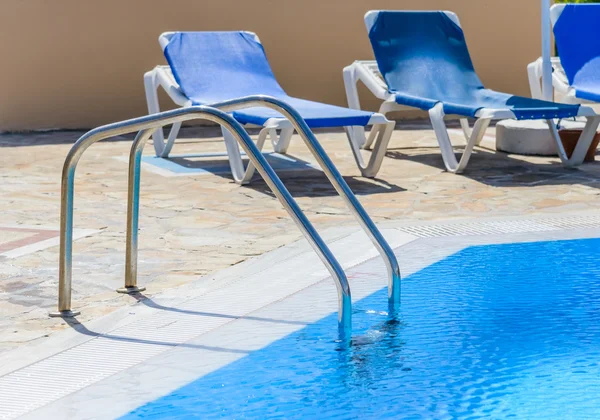 Une piscine avec chaises longues — Photo