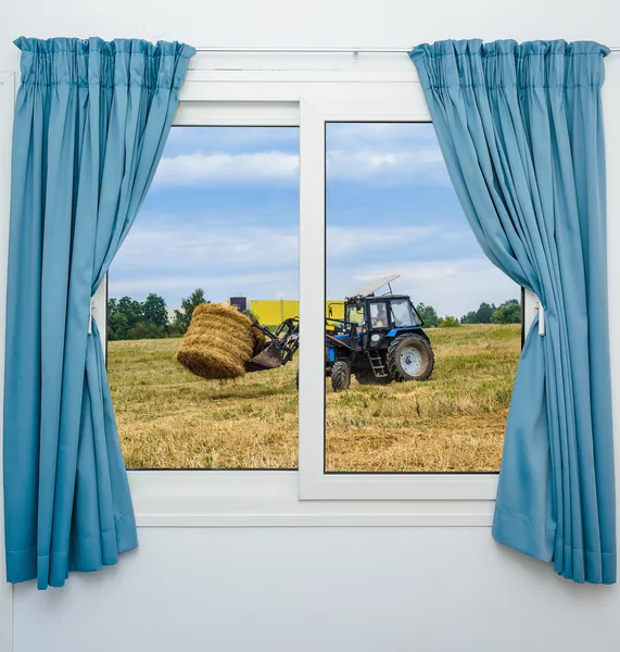 Fieno trattore rimuove la vista dalla finestra con tende — Foto Stock