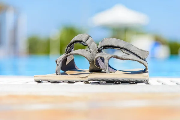 Lederen sandalen zijn aan de rand van het zwembad — Stockfoto