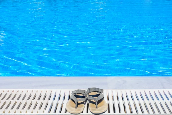 Sandálias de couro estão na borda da piscina — Fotografia de Stock