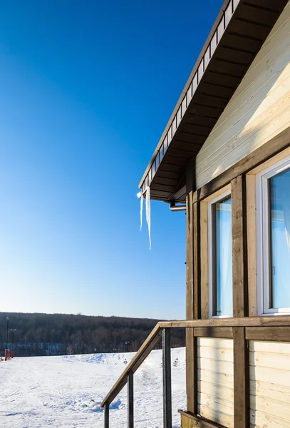 Taket på huset med hängande istappar på blå himmel bakgrund — Stockfoto