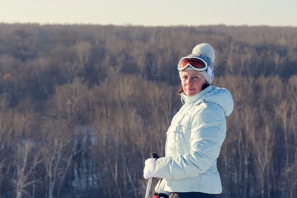 Middle-aged brunette on a hillside in a cap and ski goggles — Stock Photo, Image