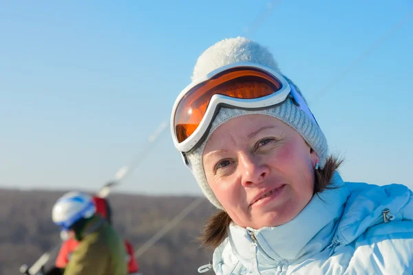 Брюнетка среднего возраста на склоне холма в кепке и лыжных очках — стоковое фото
