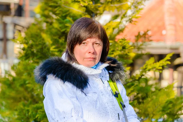 Brünette Frau mittleren Alters in eleganter weißer Jacke mit Fellkapuze — Stockfoto