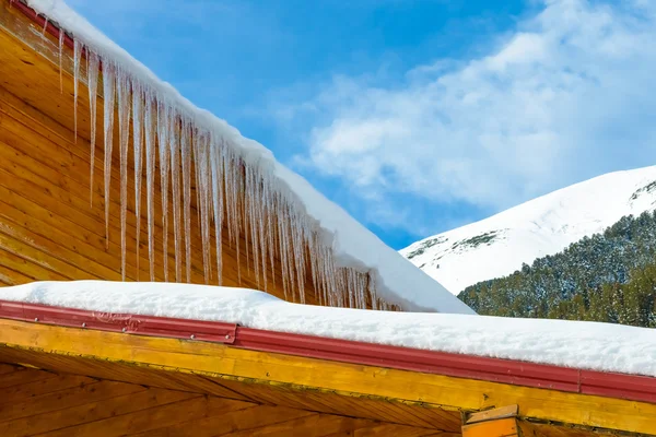 Stock image roof of the house with hanging icicles on blue sky background