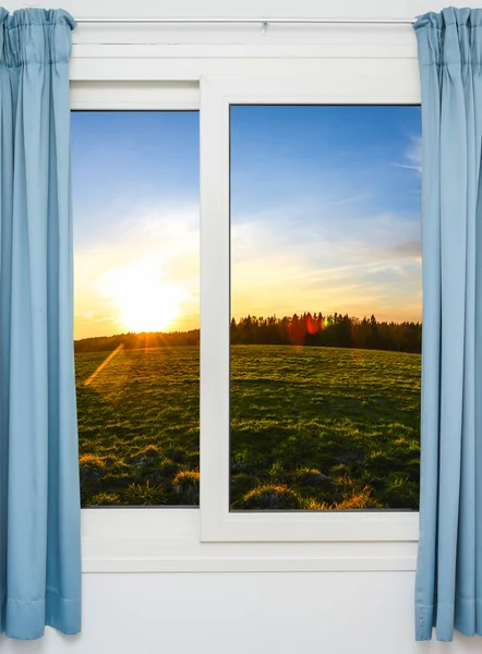 Porta aberta com vista para o prado verde iluminado pelo sol brilhante — Fotografia de Stock