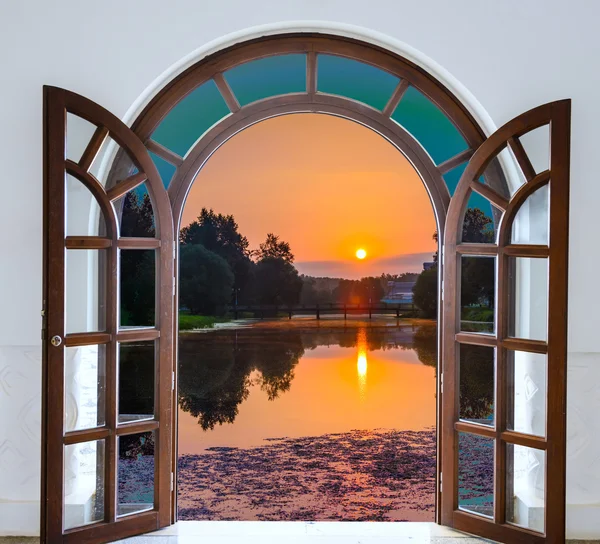 Porta aberta com vista para o prado verde iluminado pelo sol brilhante — Fotografia de Stock