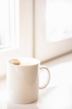 Pencere kenarında beyaz porselen kahve fincanı.