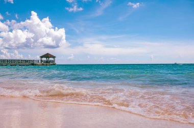 Karayip Denizi 'ndeki bir rıhtımda palmiye yapraklarından bir çatısı olan ahşap bir çardak.