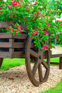 Bahçesinde çiçekler olan dekoratif ahşap bir araba.